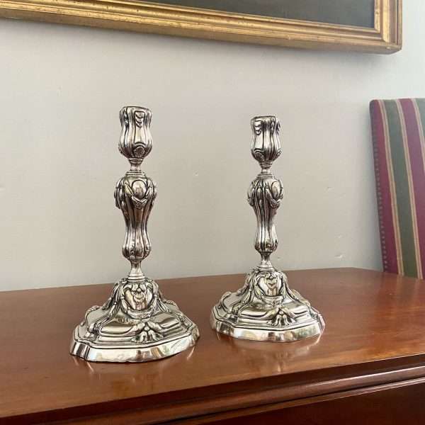 a pair of silvered bronze candlesticks on a side table