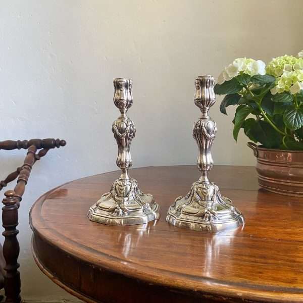 a pair of silvered bronze candlesticks on a round table
