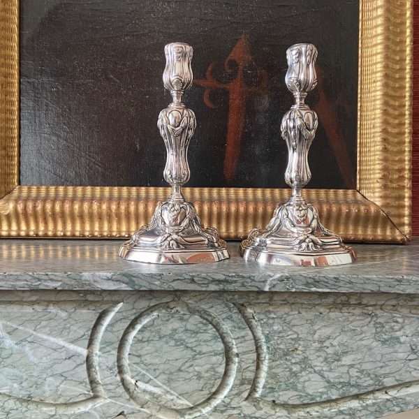 a pair of silvered bronze candlesticks on a mantelpiece